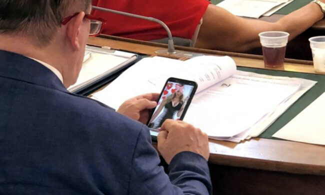 Consigliere comunale paparazzato in aula mentre guarda una maggiorata sul cellulare