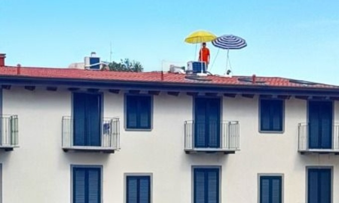 Due uomini sul tetto di un palazzo sotto due ombrelloni, ma non stavano prendendo il sole…